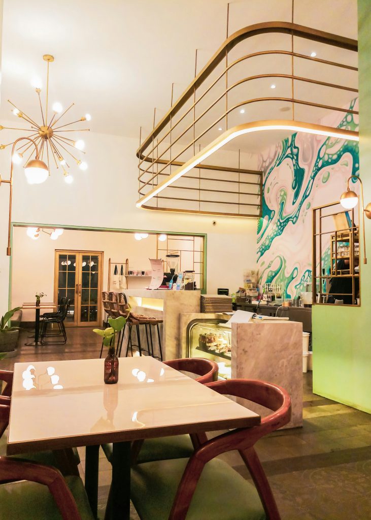 Contemporary café interior featuring marble counters, bespoke lighting, and a vibrant feature wall, completed as part of a commercial property fit-out project.