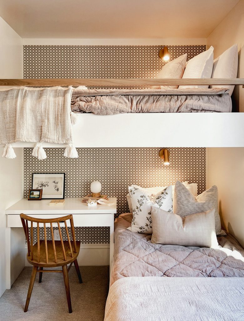 Built-in bunk bed with lower single bed, upper sleeping area, and integrated desk with wooden chair in a cosy, modern bedroom.